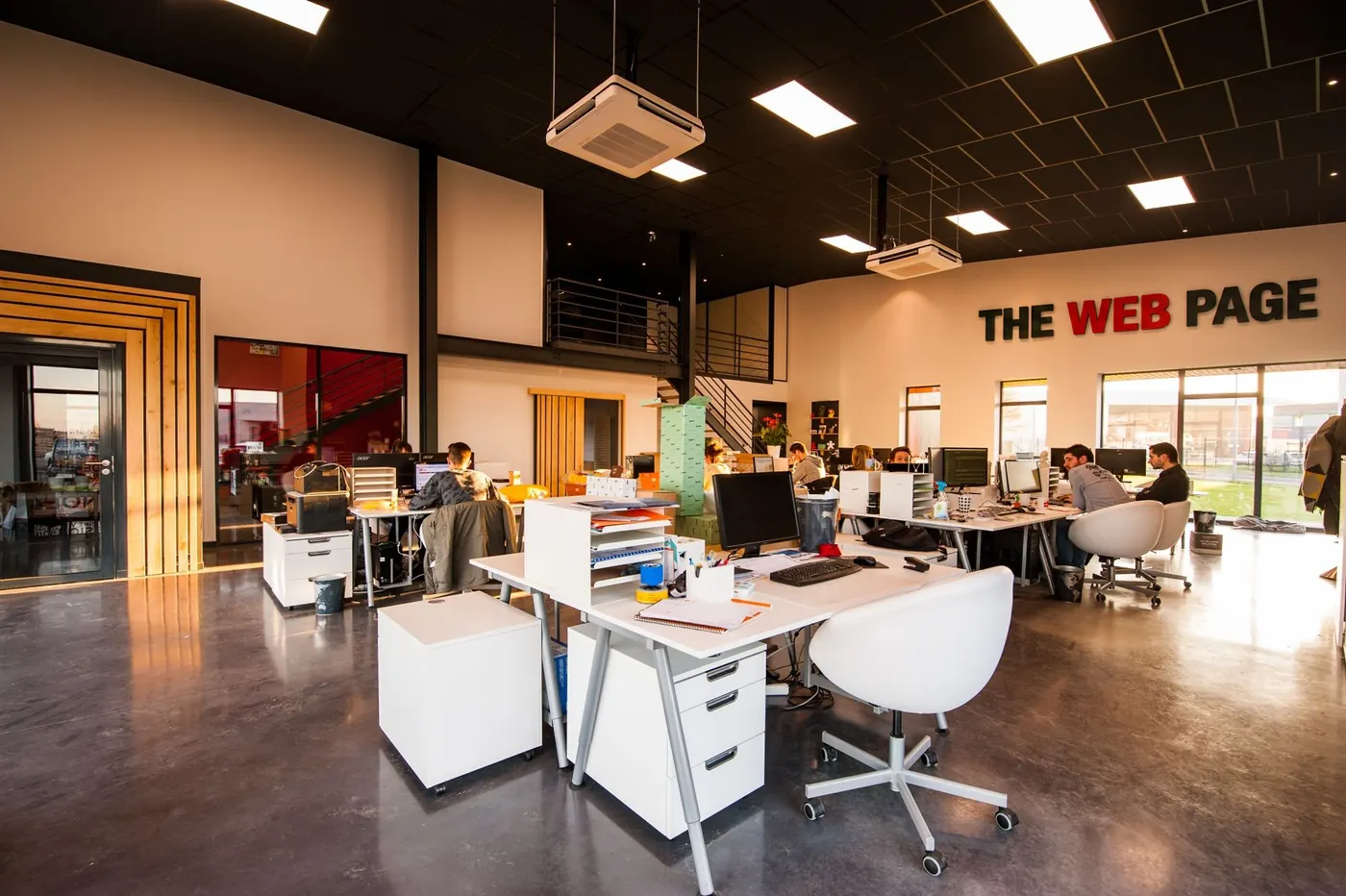 Open-plan office with The Web Page sign on the wall